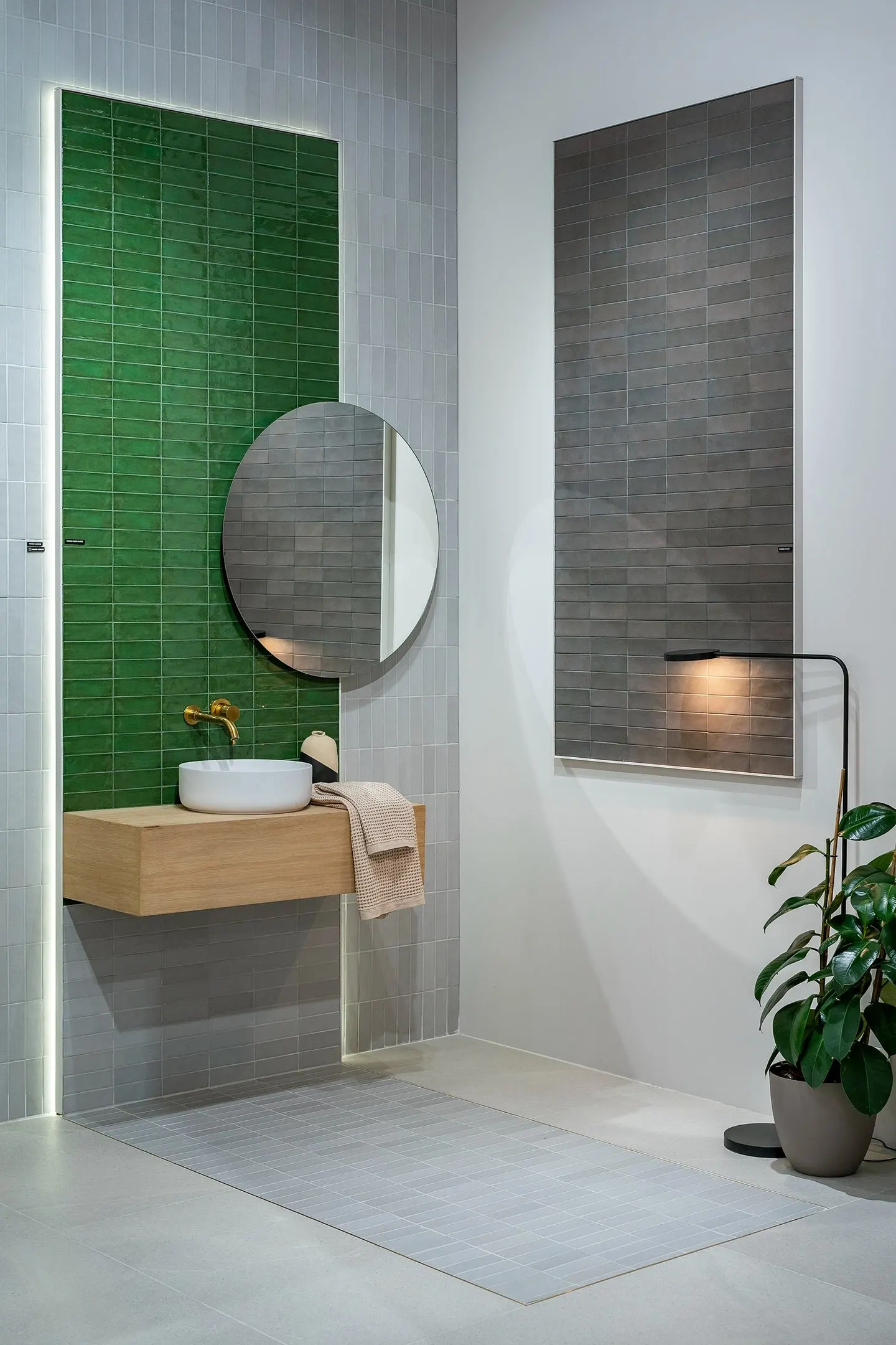 Ambiente de baño en Cersaie 2023 con pared verde alicatada y espejo redondo