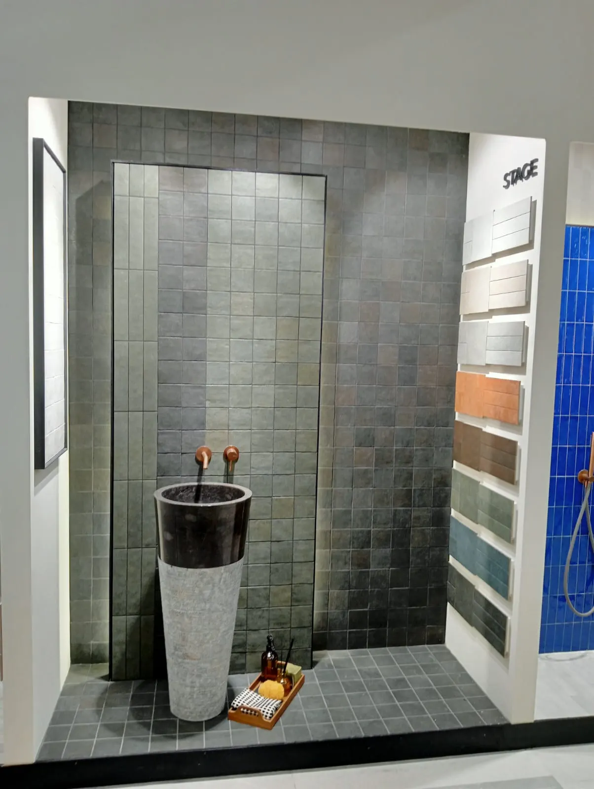 Ducha de exposición alicatada en gris con lavabo de piedra y muestrario